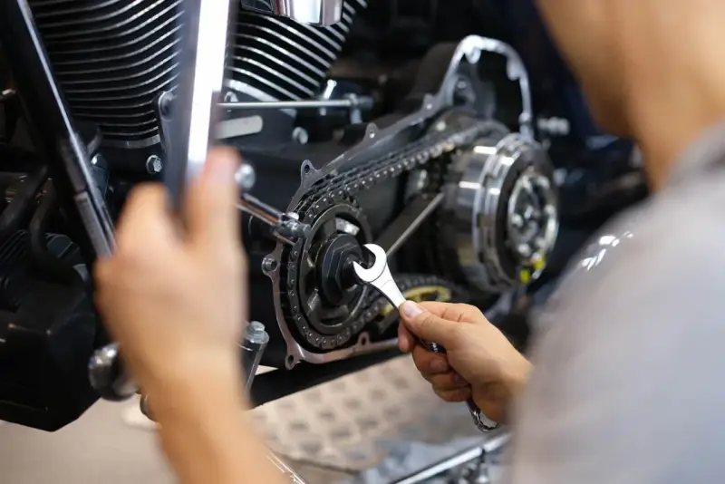 Mechaniker repariert Motorrad-Steuerkette. Die Kosten für den Wechsel der Steuerkette sind hier ein wichtiger Faktor.